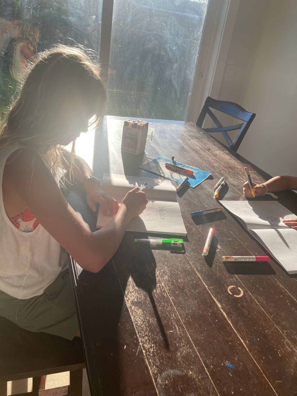 A family coloring at the dining table in the Beautiful Words coloring book, showcasing a lifestyle view of the book in use.